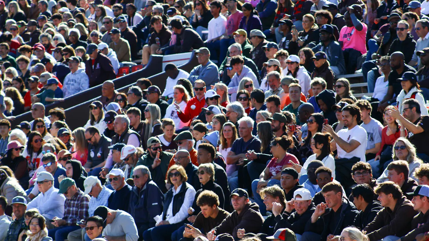 Photo of a crowd sitting in elevated stands at a football game.